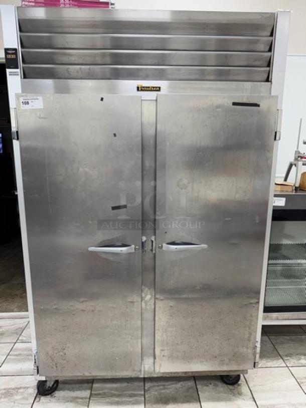 Traulsen 2-door freezer, model G22010, stainless steel, non-consistent functionality, visible surface wear, on casters.