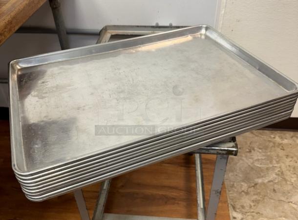 10 full-size sheet pans stacked; metal construction, used condition, slight wear visible; ideal for commercial baking.