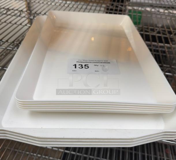 Assorted heavy-duty plastic serving trays on a metal rack, quantity 9, labeled with auction number 135.