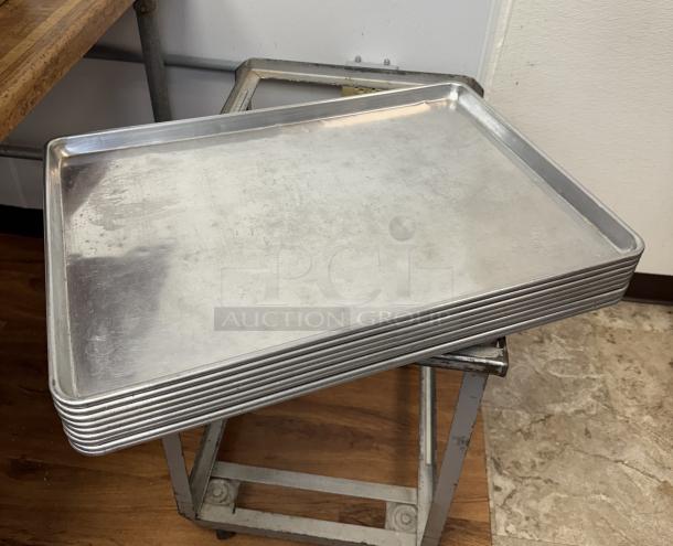 Stack of 10 full-size aluminum sheet pans in good used condition, ideal for commercial baking.