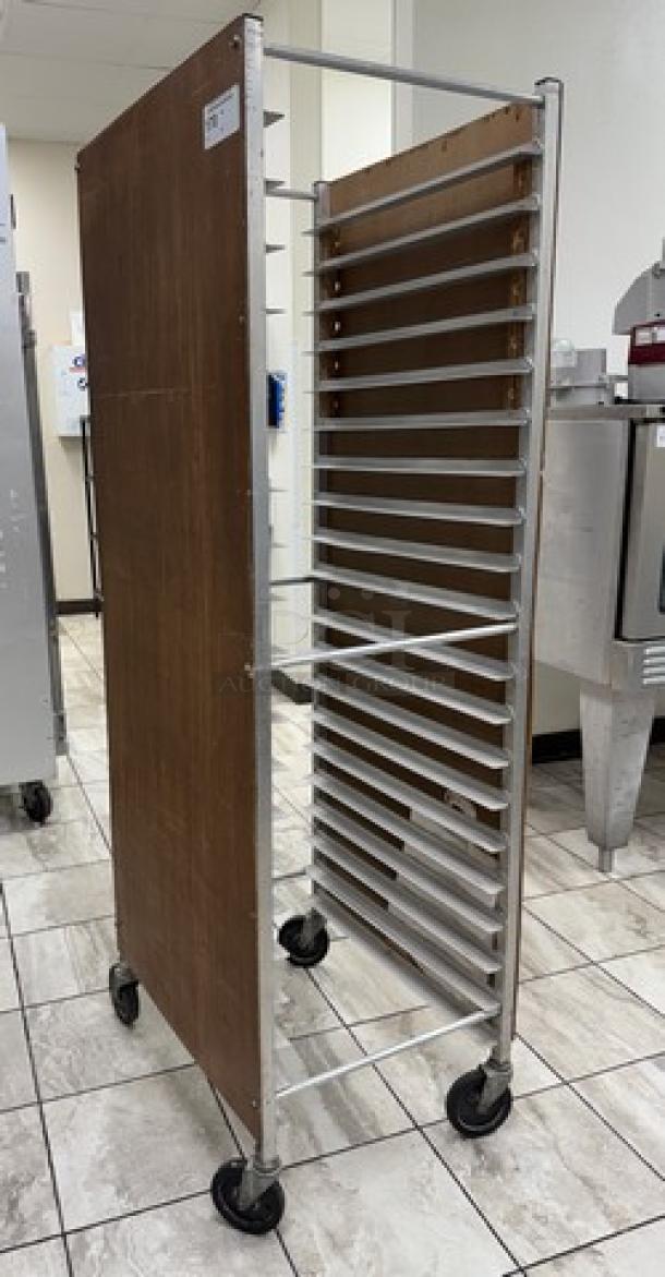 Rolling sheet pan rack with multiple aluminum slots, wood panel sides, and swivel casters. Good condition. Ideal for bakery use.