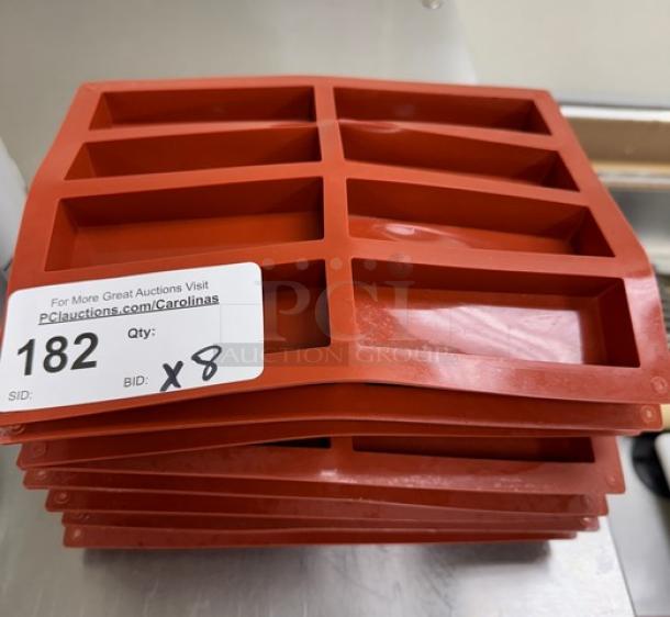 Stack of red silicone baking molds, rectangular shape, 8 pieces, auction tag indicates quantity as 8, item ID 182.