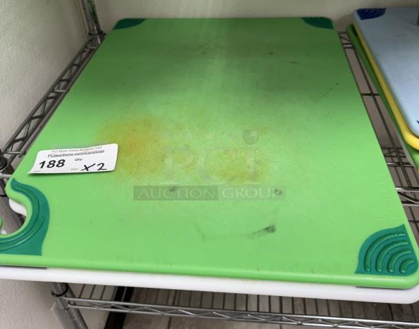Green plastic cutting board, well-used, with rubber corner grips. Auction tag reads "188 x 2 qty".