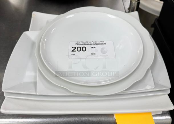 Assorted white china serving plates with subtle scalloped edges, stacked neatly. Condition appears excellent. Auction label showing quantity 200.