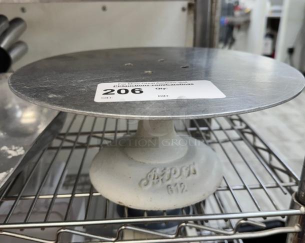 Cast iron cake stand with round metal top, marked "A.P.O.V. 612." Auction lot tag number 206 visible.