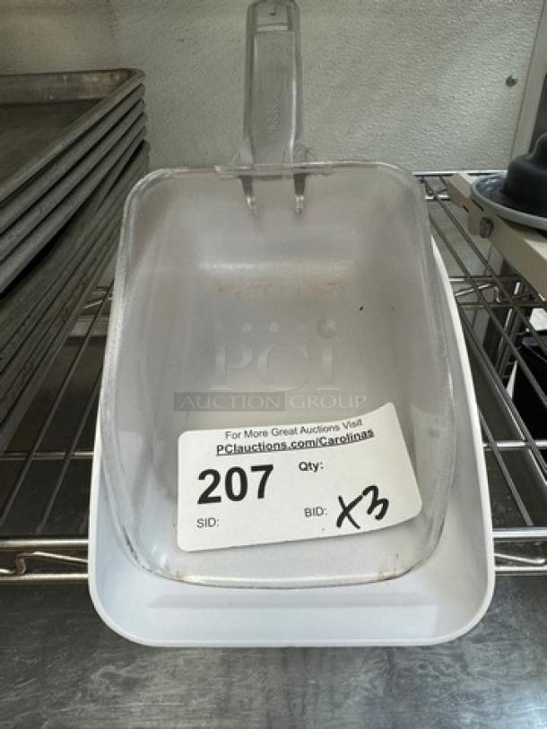 Clear plastic dry good scoop with a handle, quantity 3, auction lot number 207. Used condition, ideal for bulk dispensing.