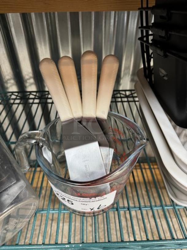 Glass 4-cup measuring cup with four spatulas, gently used. Auction lot tagged "6 x Bid." Clear volume markings visible.