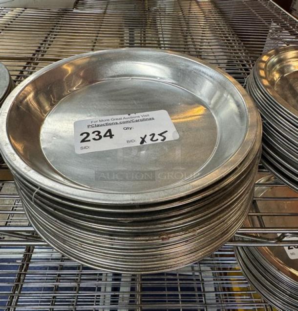 Stack of 25 metal pie pans with label "234, Bid x25" on top pan, in good condition on wire shelving.