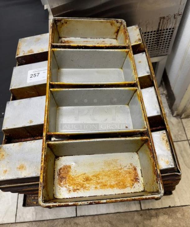 Set of 12 vintage bread pans with visible wear and rust, numbered tag 257. Ideal for bakery use or as collectibles.