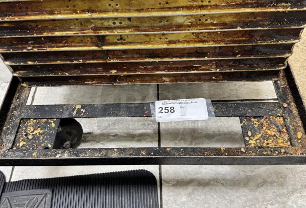 Twelve metal bread pans in used condition, stacked on a rack. Auction label reads "258." Signs of wear and baking residue visible.