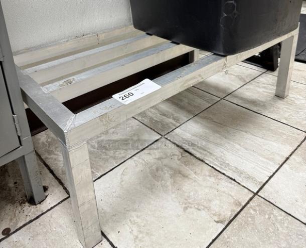 Aluminum dunnage rack with slatted surface, minor wear, sturdy legs. Auction tag 260 visible. Ideal for storage.