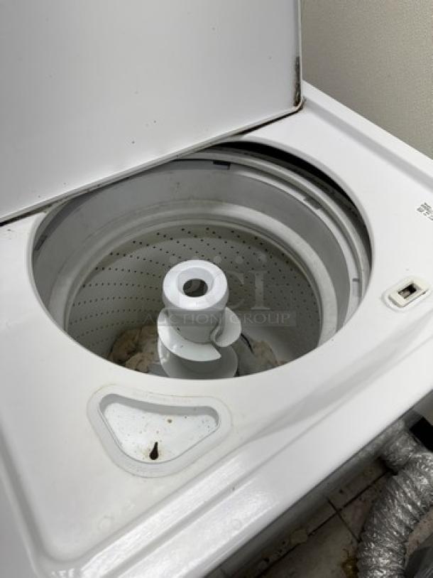 Whirlpool clothes washer, top-loading, visible agitator, white finish, open lid, appears used with minor wear.