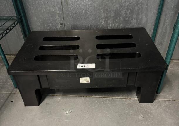 Black dunnage rack with slotted top, used condition. Features a label with unidentified text and an auction tag reading "265."