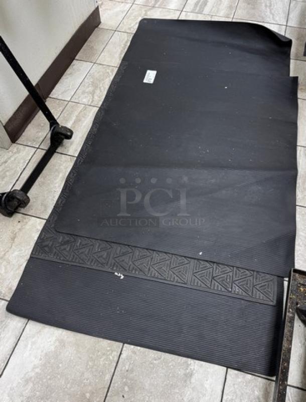 Black floor mats, set of four, featuring textured geometric pattern, minor wear, suitable for indoor use.