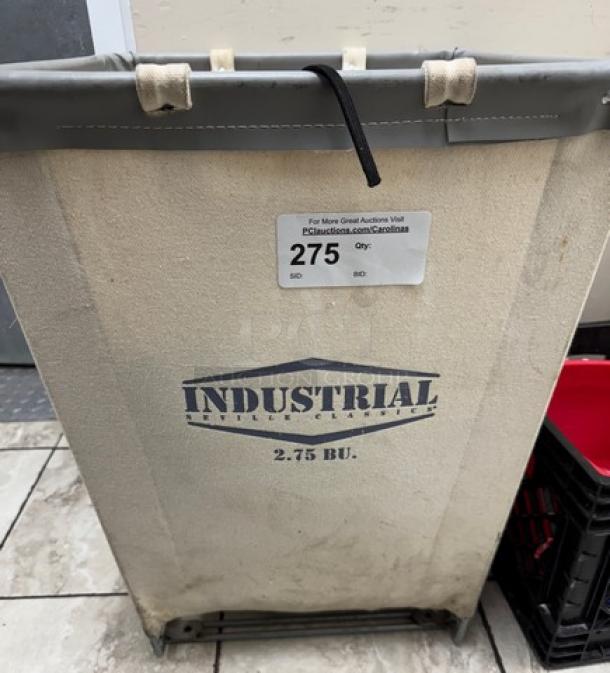 Rollable linen basket, industrial style, 2.75 BU capacity, metal frame, beige fabric with visible auction tag.