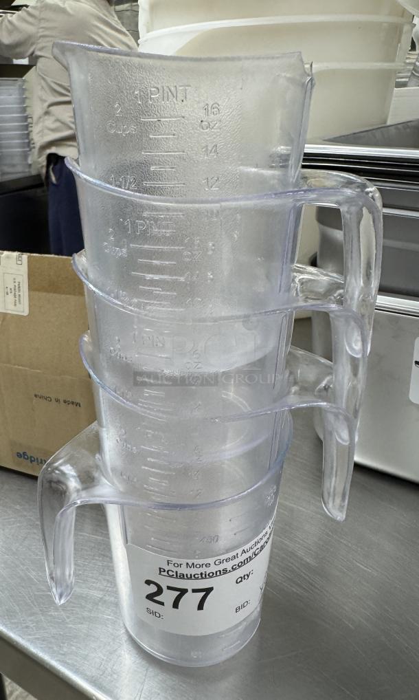 Stack of four clear 1-gallon plastic pitchers with measurement markings, auction tag labeled 277, in good condition.