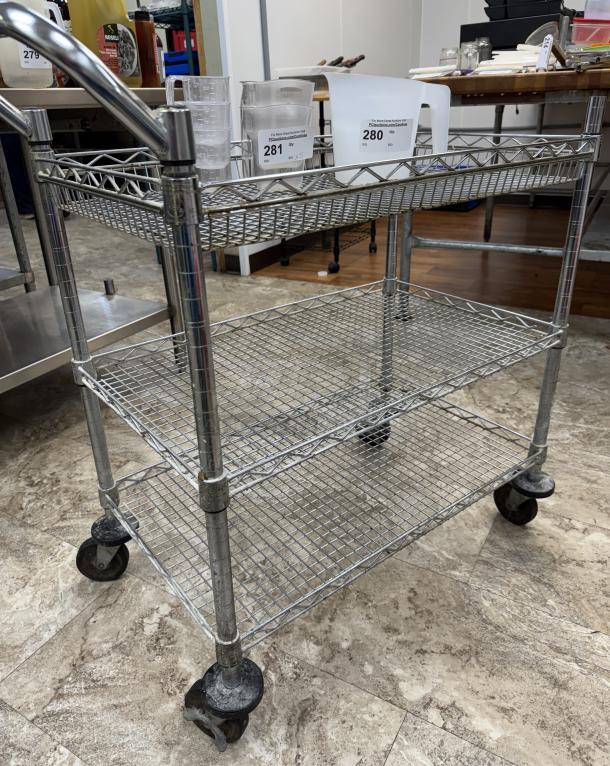Rolling wire cart with 3 shelves, chrome finish, industrial wheels, good condition, ideal for storage and transport.