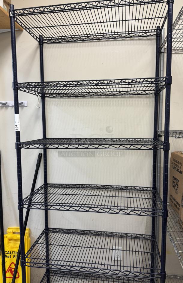 Black wire rack with 6 shelves, sturdy metal construction, used condition. Dimensions: adjustable height and shelves. Item tag visible.