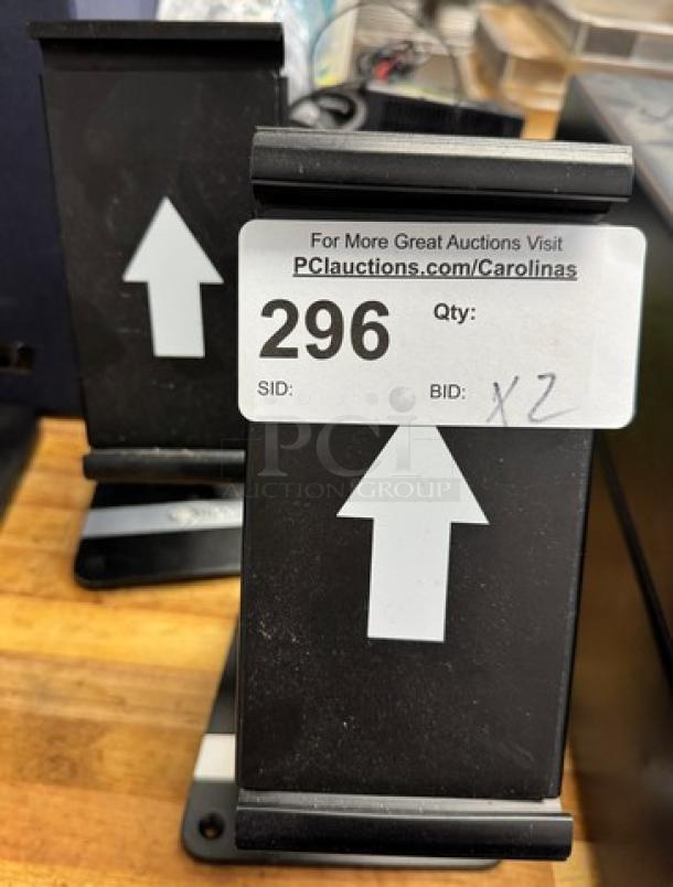Black iPad holders with adjustable grips and base; labeled with auction tag "296" for identification.