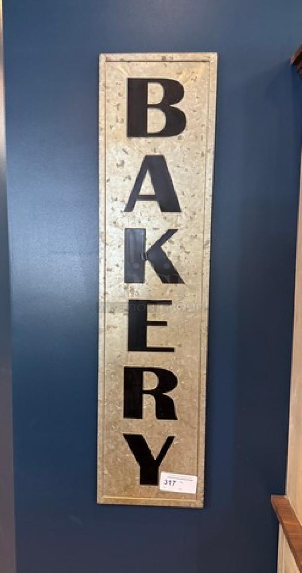 Tin Bakery wall sign, vertical orientation, gray metal with large black letters spelling "BAKERY," grainy texture, tag visible.