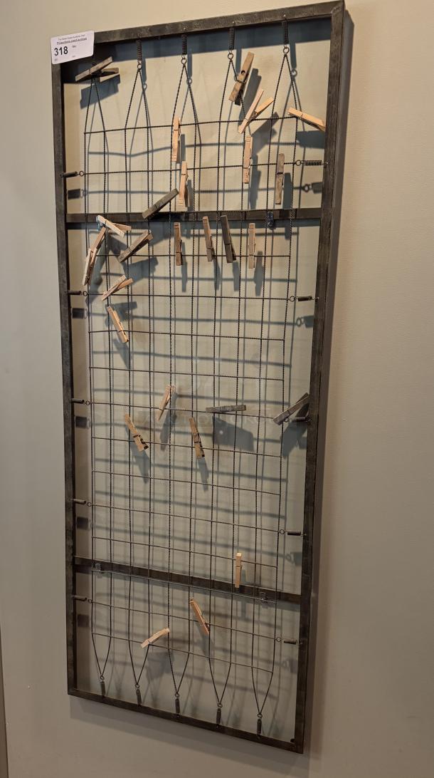 Metal and wood wall rack with grid design, featuring attached clothes pins, auction tag with number 318 visible.