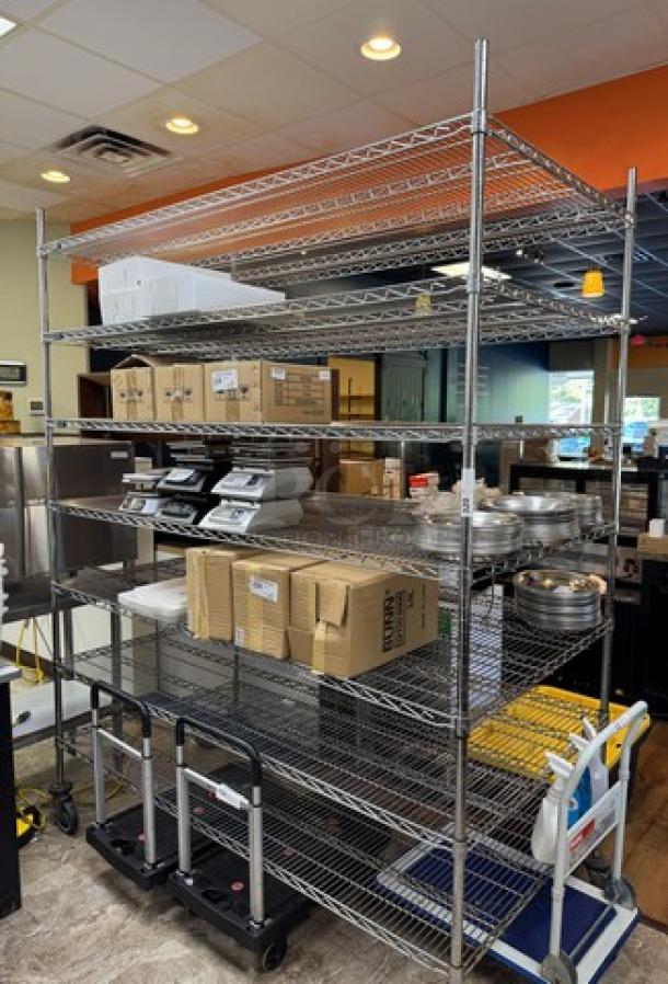Rolling wire rack with multiple shelves, chrome finish, excellent condition, fitted with wheels for easy mobility, ideal for storage.