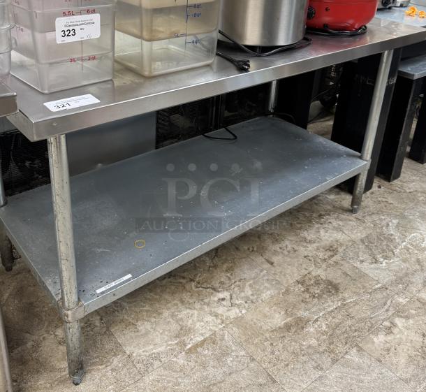 Stainless steel table with galvanized undershelf, used, durable construction, slight wear on legs, auction labels visible.
