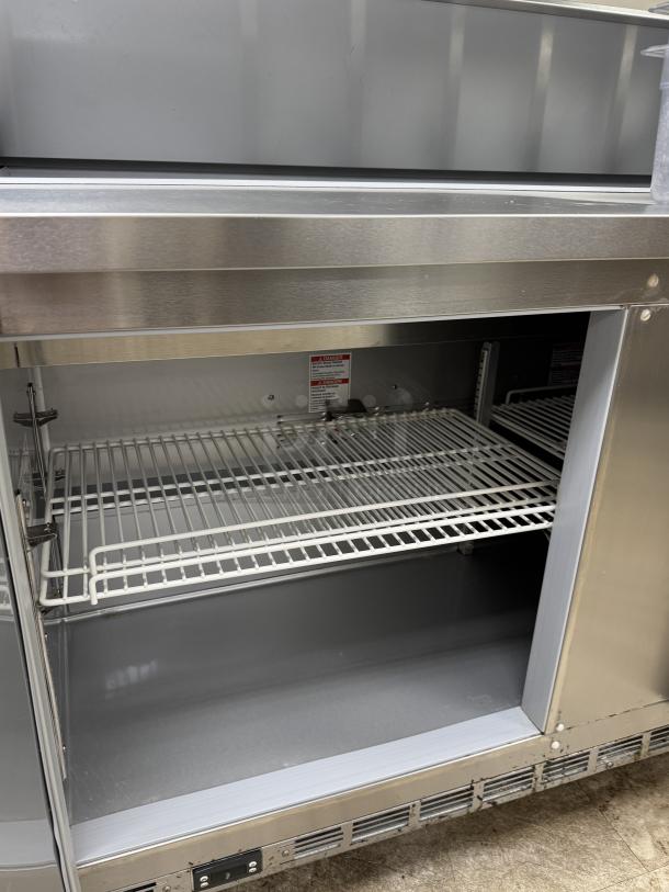 Beverage Air refrigerated prep table, Model SPE60HC-16, stainless steel, tested working, with wire shelving and interior storage.