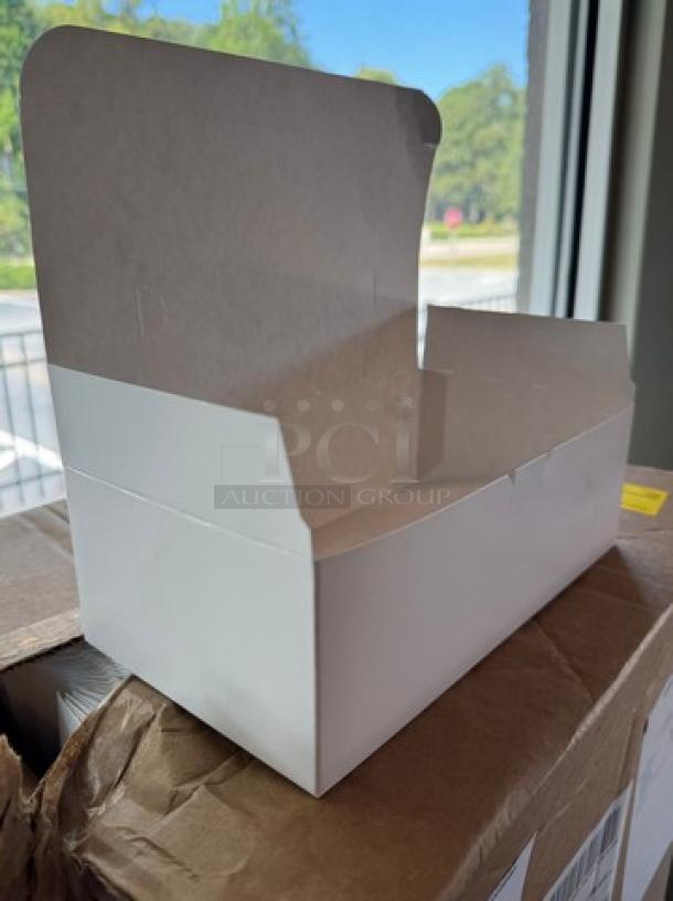 Small white disposable bakery box, new condition, open lid, cardboard material, shown on a case.