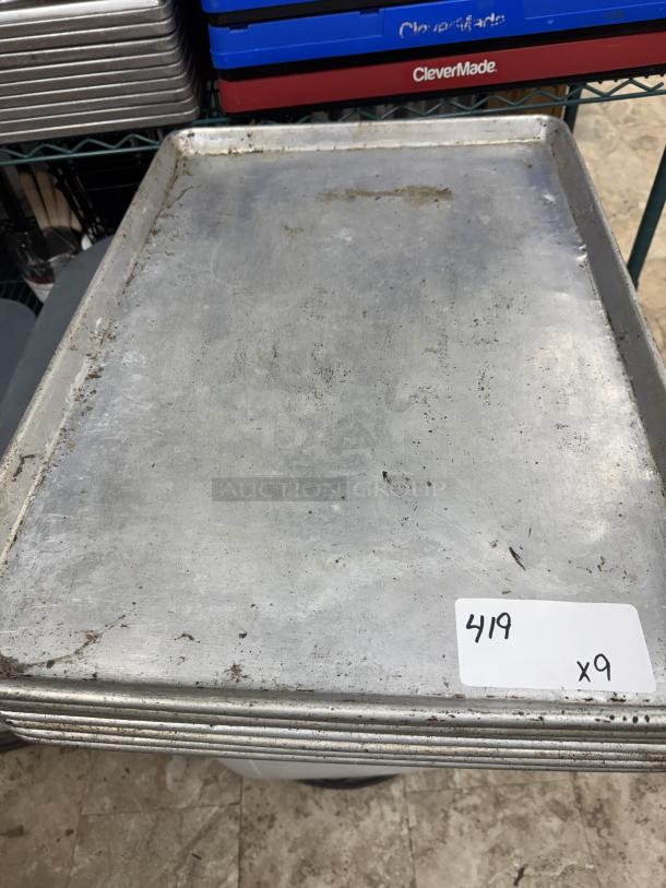 Full-size sheet pans, nine total, metal with visible wear. Stackable. Label reads "419 x9". Ideal for bulk baking.