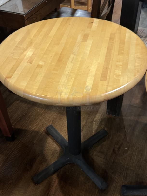 Round wooden dining table with a natural finish, metal pedestal base, in good condition. Ideal for small spaces.
