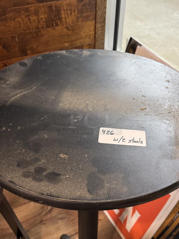 Black round table with visible wear and dust, labeled "426 w/2 stools." Includes two matching stools.