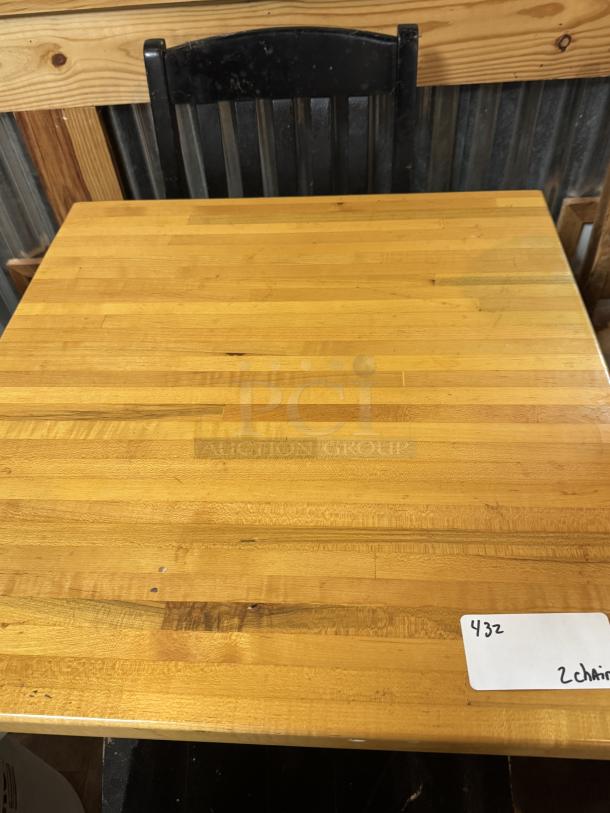 Wooden dining table with a smooth finish, paired with two black chairs. Visible tag reads "432, 2 chairs." Good condition.