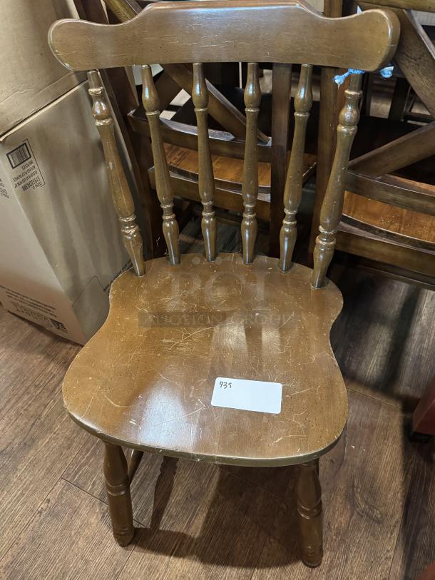 Wooden dining chair with spindle back design, shows signs of wear with scratches. Seat labeled "435".