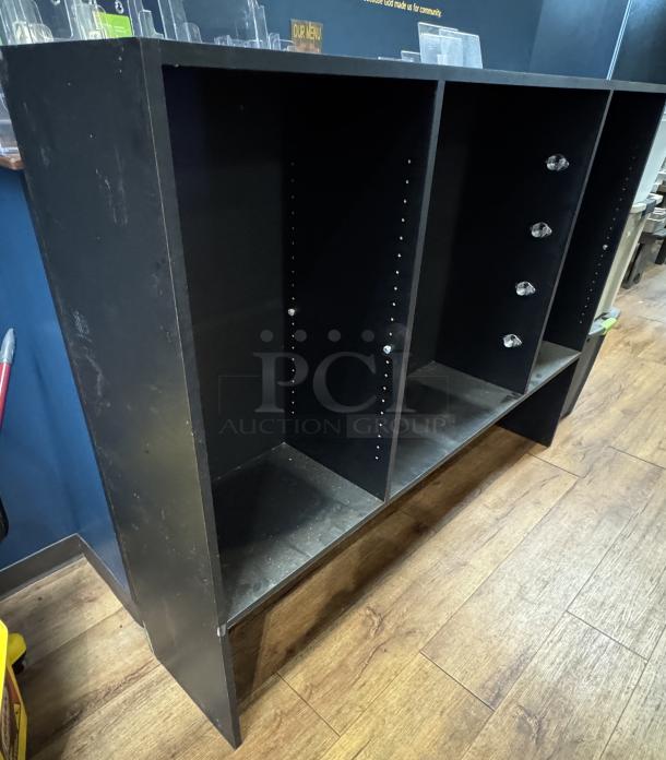 Black display case with three open shelves and adjustable peg holes. Some wear and visible scratches.