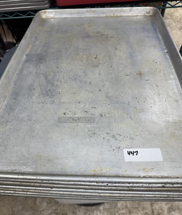 Full-size aluminum sheet pans, set of 9, used condition with visible wear and minor scratches. Tag labeled "447".