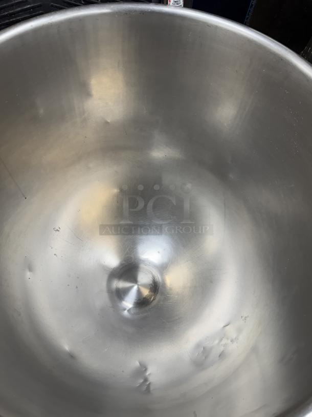 120 Qt. stainless steel mixing bowl with visible dents and scratches, includes a rolling dollie for easy transport.