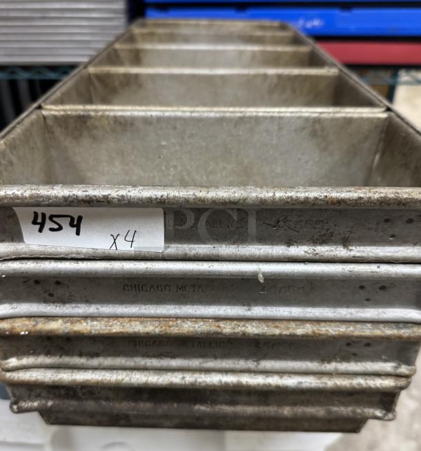 Set of four 5-loaf bread pans by Chicago Metallic, showing wear and marks. Label reads "454 x4." Ideal for baking.