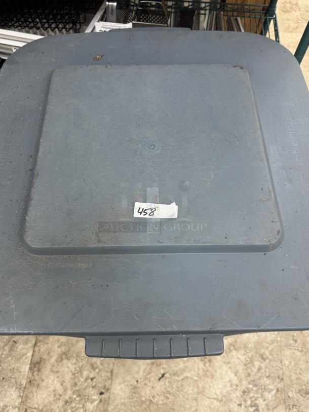 Rubbermaid 40 Gal dry storage container with lid, moderate wear, visible dust, labeled "458." Includes dollie for mobility.