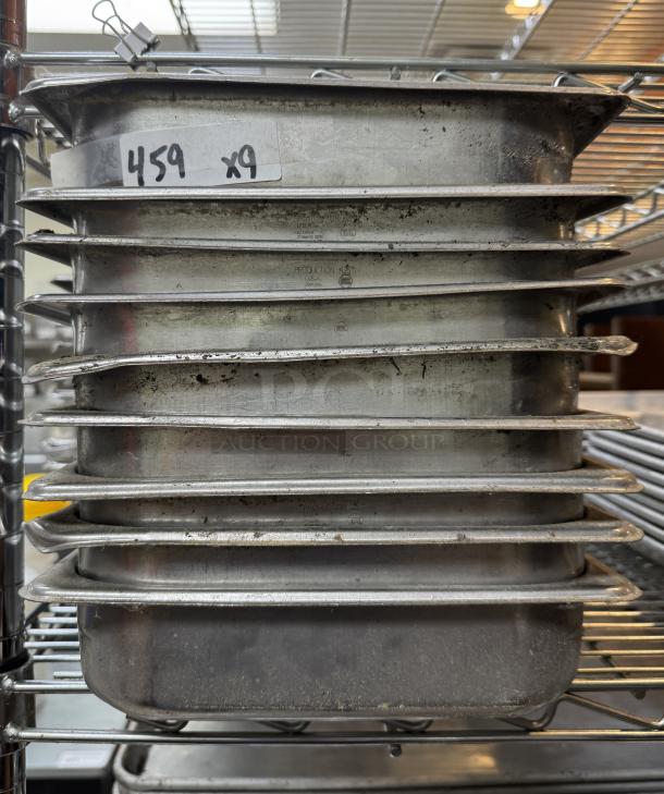 Nine stainless steel half pans stacked, showing slight wear, labeled "459 x9," ideal for catering or food service use.