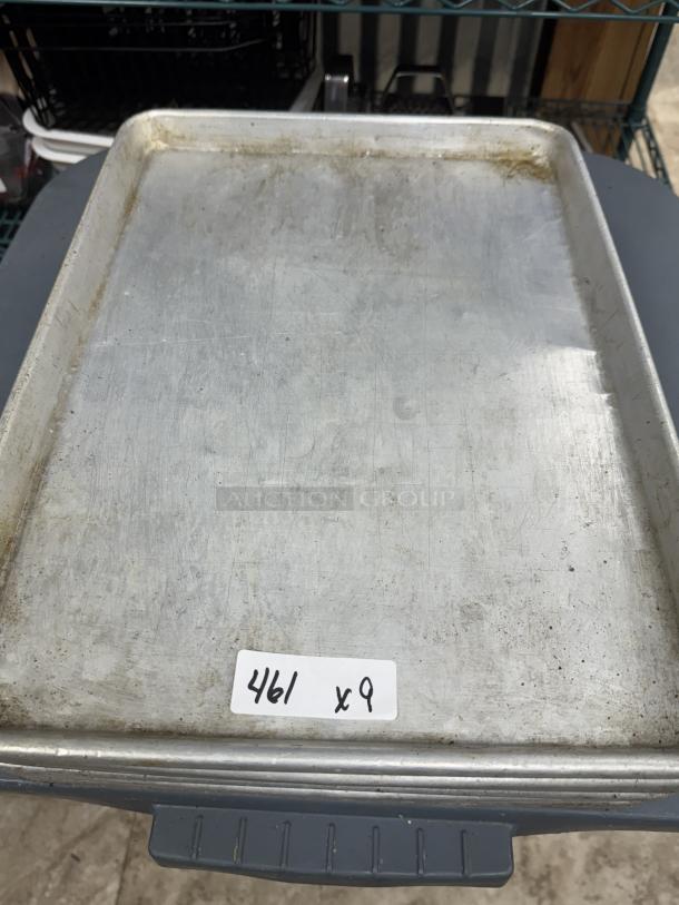 Stainless half size sheet pans, set of 9, showing slight wear. Label indicates "461 x 9". Ideal for baking needs.