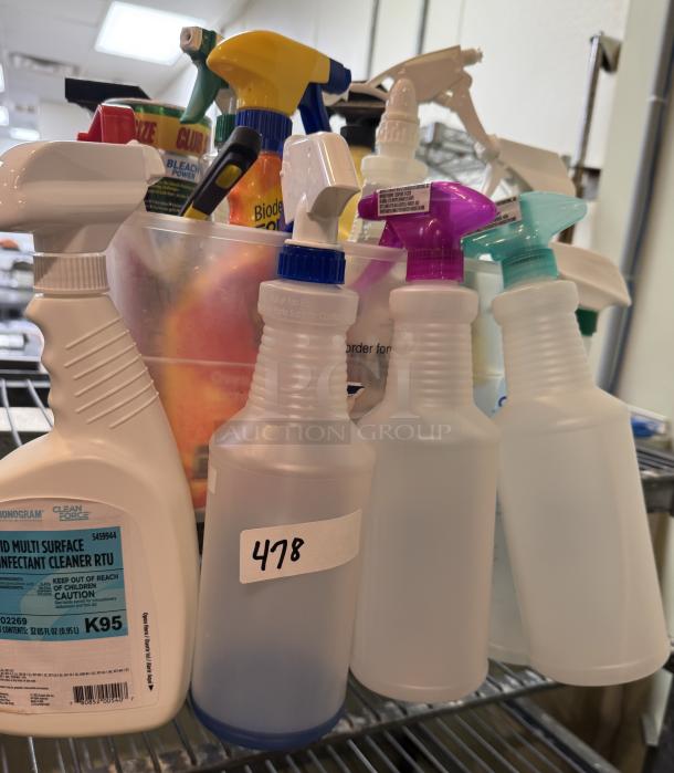 Assorted cleaning supplies with multiple spray bottles, one labeled "Monogram Clean Force Disinfectant Cleaner," in bucket.
