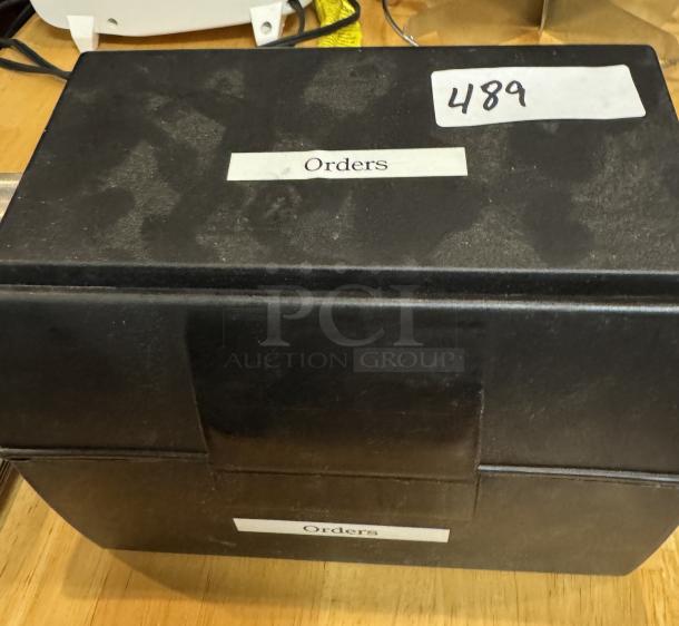 Black recipe box with dividers, labeled "Orders," item number 489 on top, in used condition.