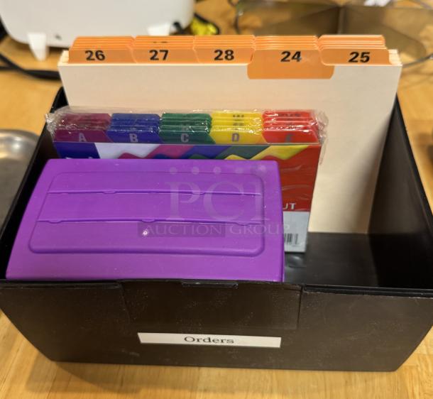 Black recipe box with dividers, labeled sections 24-28, includes colorful index tabs A-F. Labeled "Orders" on the outside.