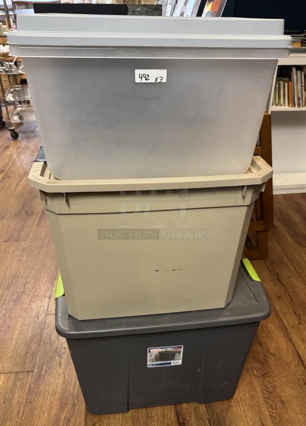 Three large plastic storage totes stacked, various colors and visible labels. Slight wear, ideal for storage solutions.