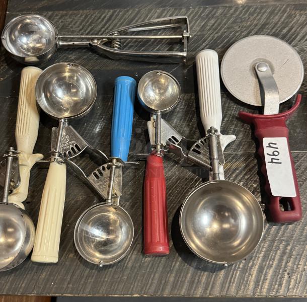 Assorted serving scoops and pizza cutter, various colored handles, stainless steel, good condition, item labeled "141."