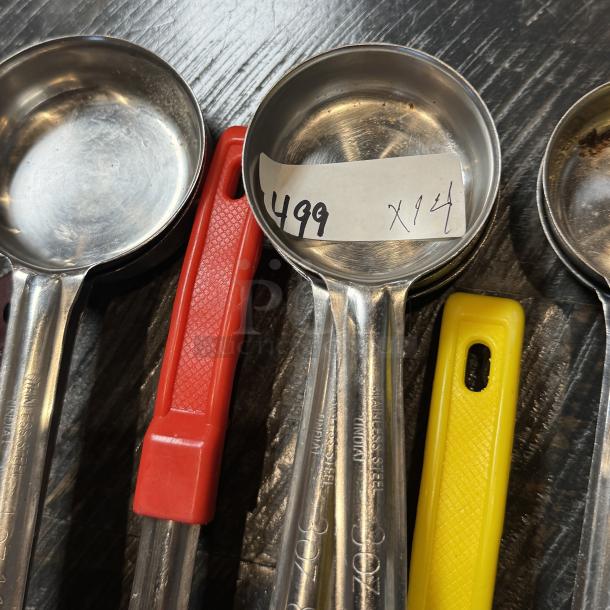 Assorted stainless steel serving ladles and one spatula with colored handles, marked "499 x14" on one ladle.