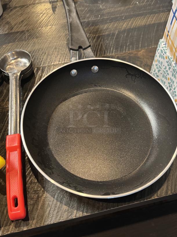 Tramontina 10" frying pan, black non-stick surface, sturdy handle; shown with measuring spoon. Excellent condition.