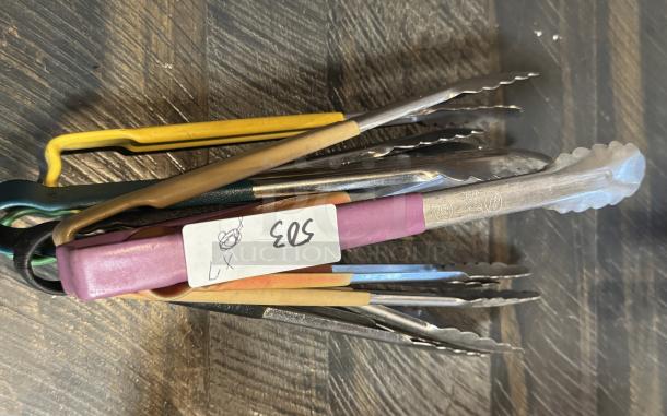 Assorted metal tongs, 7 pieces with colored grips, visible label "503". Used condition, stainless steel.