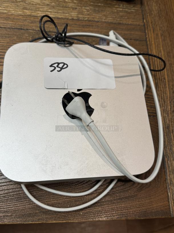 Apple Mac Mini, tested and working, shown with power cable. Slight surface wear, sticker with "SSD" marking visible.